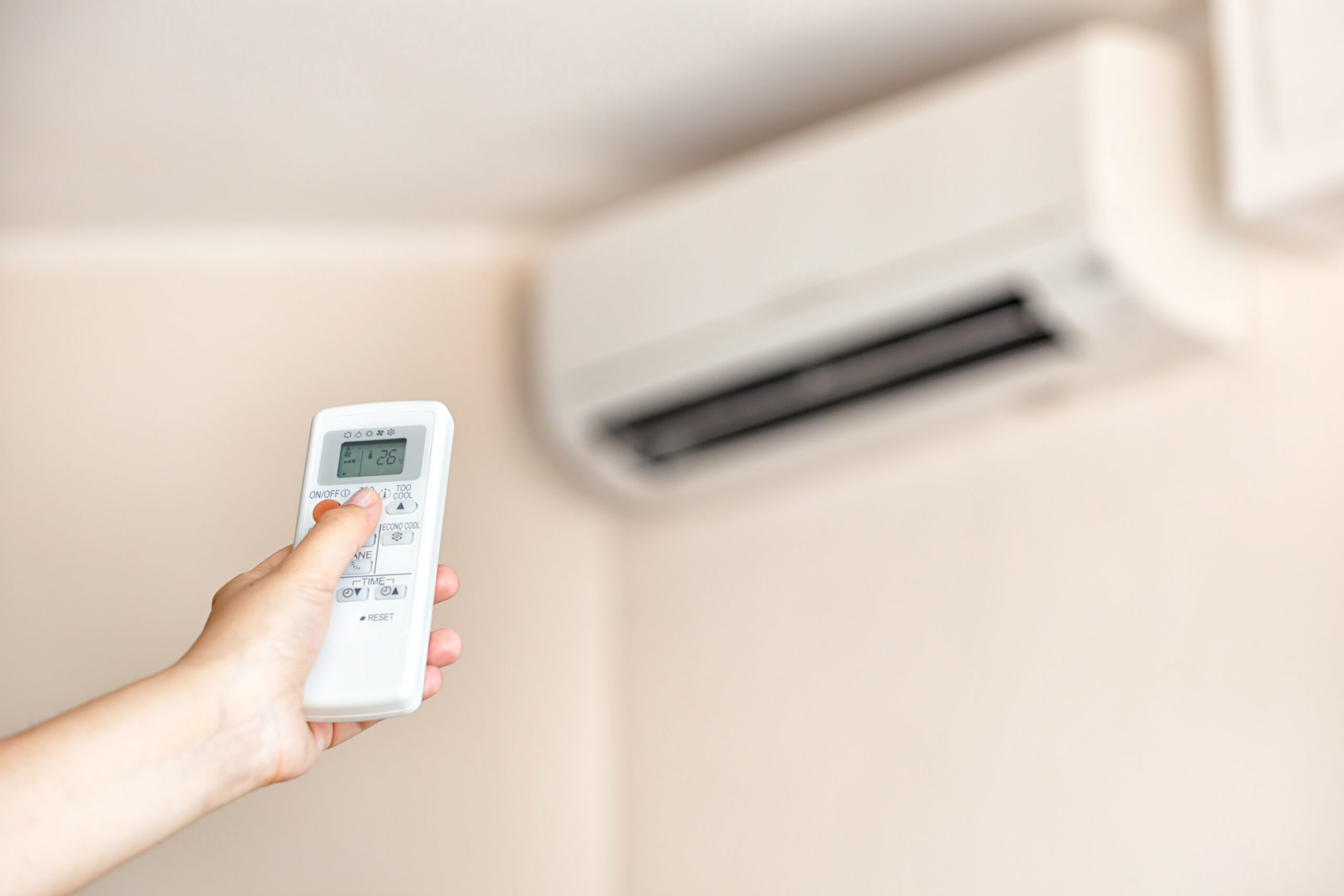 Closeup of a hand using a remote to activating air conditioning machine.