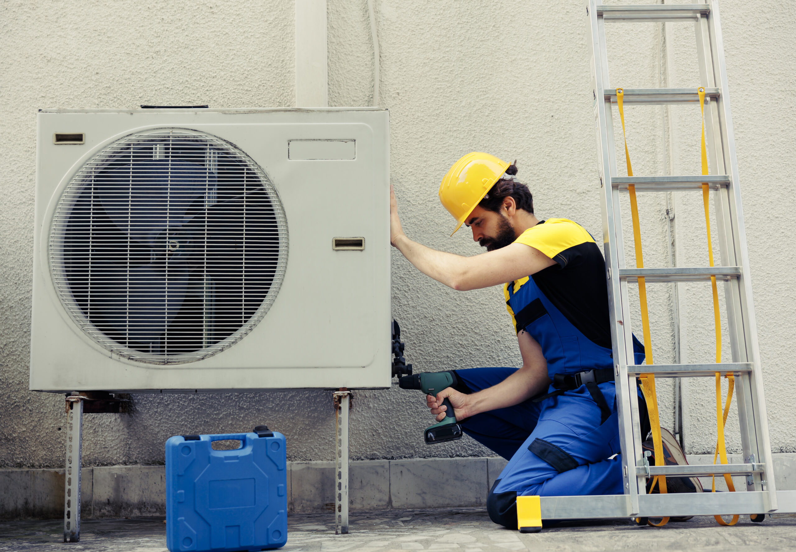 Competent repairman starting work on defective air conditioner, using handheld drill to disassemble condenser metal coil panel. Precise mechanic dismantling hvac system to check for dirt